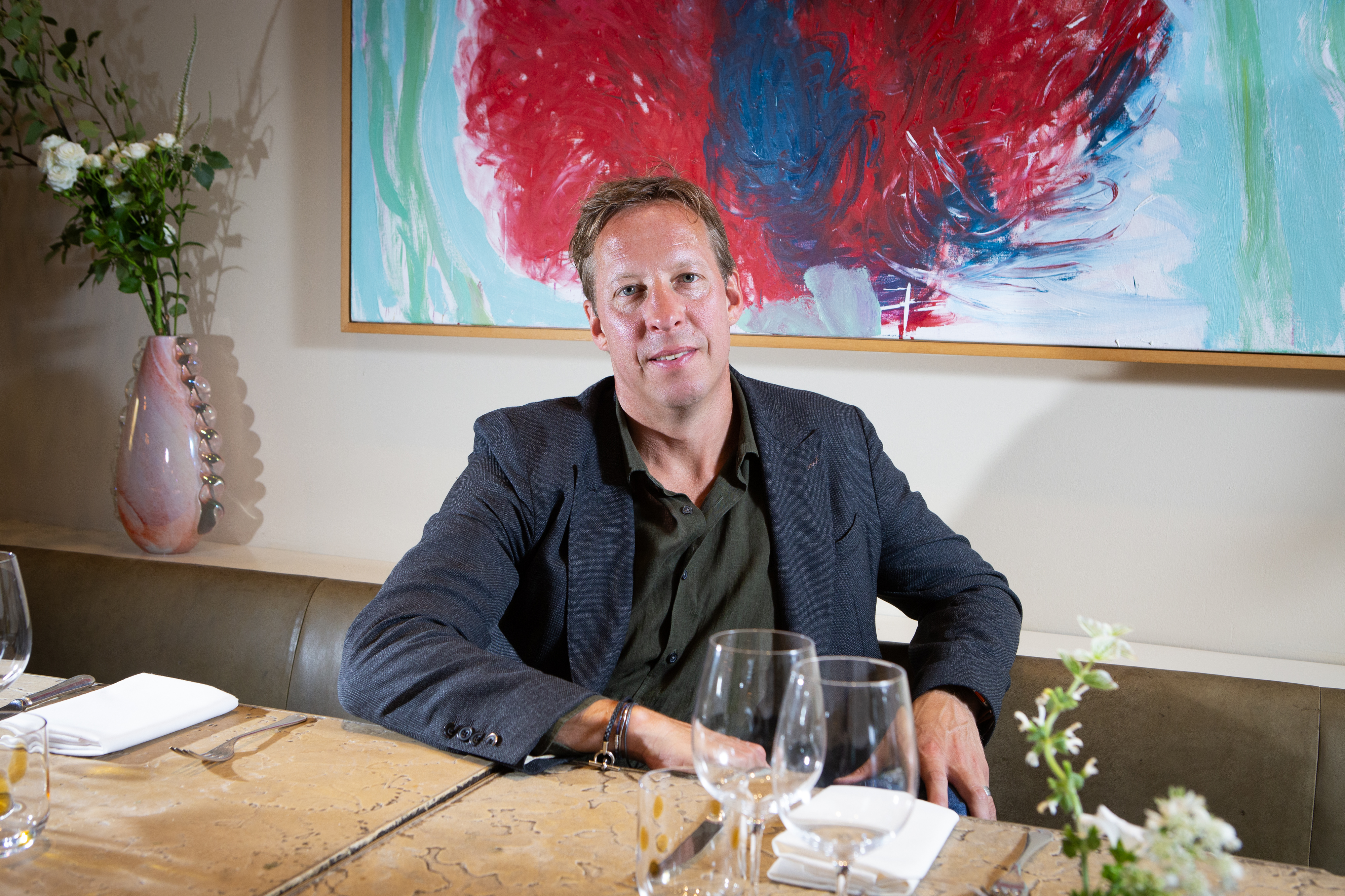 a man sits at a table in front of a painting
