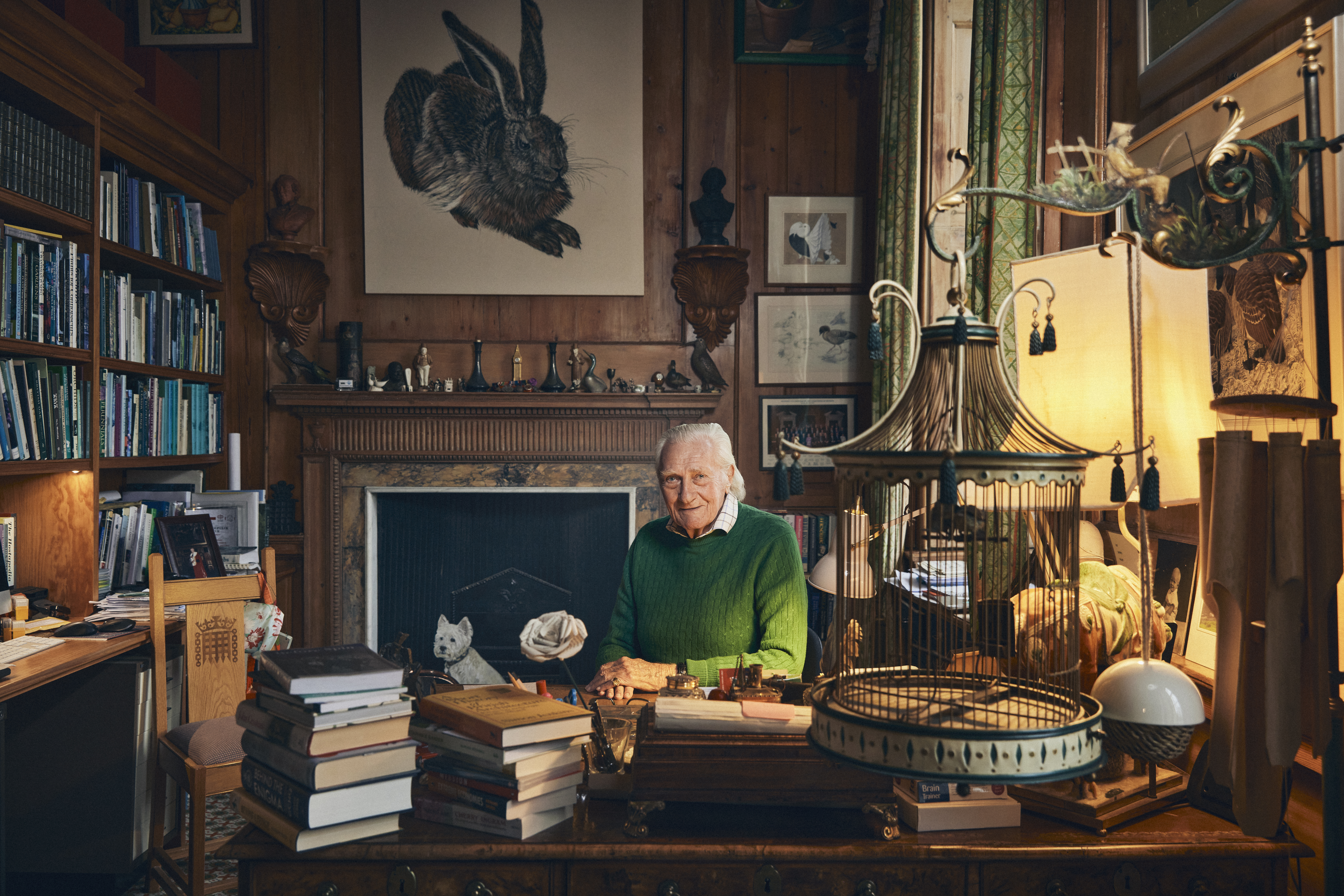 Portrait of Michael Heseltine sitting at his desk in his study.